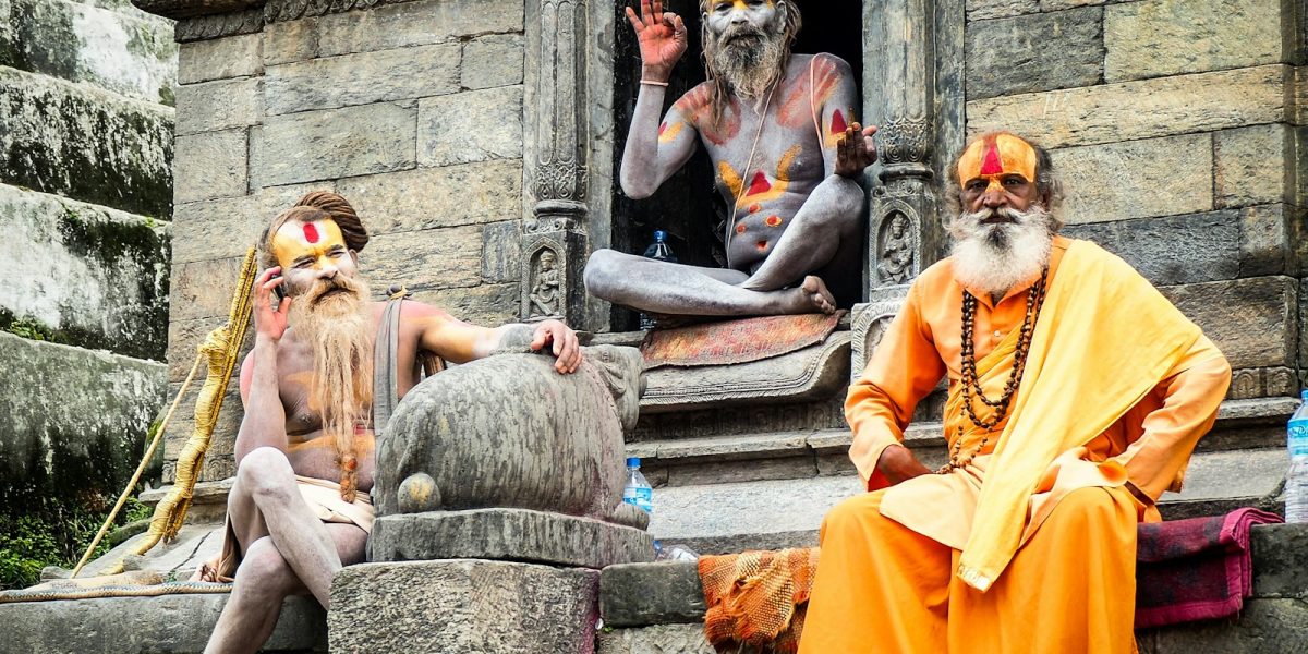 three monks sitting on concrete temple during daytime